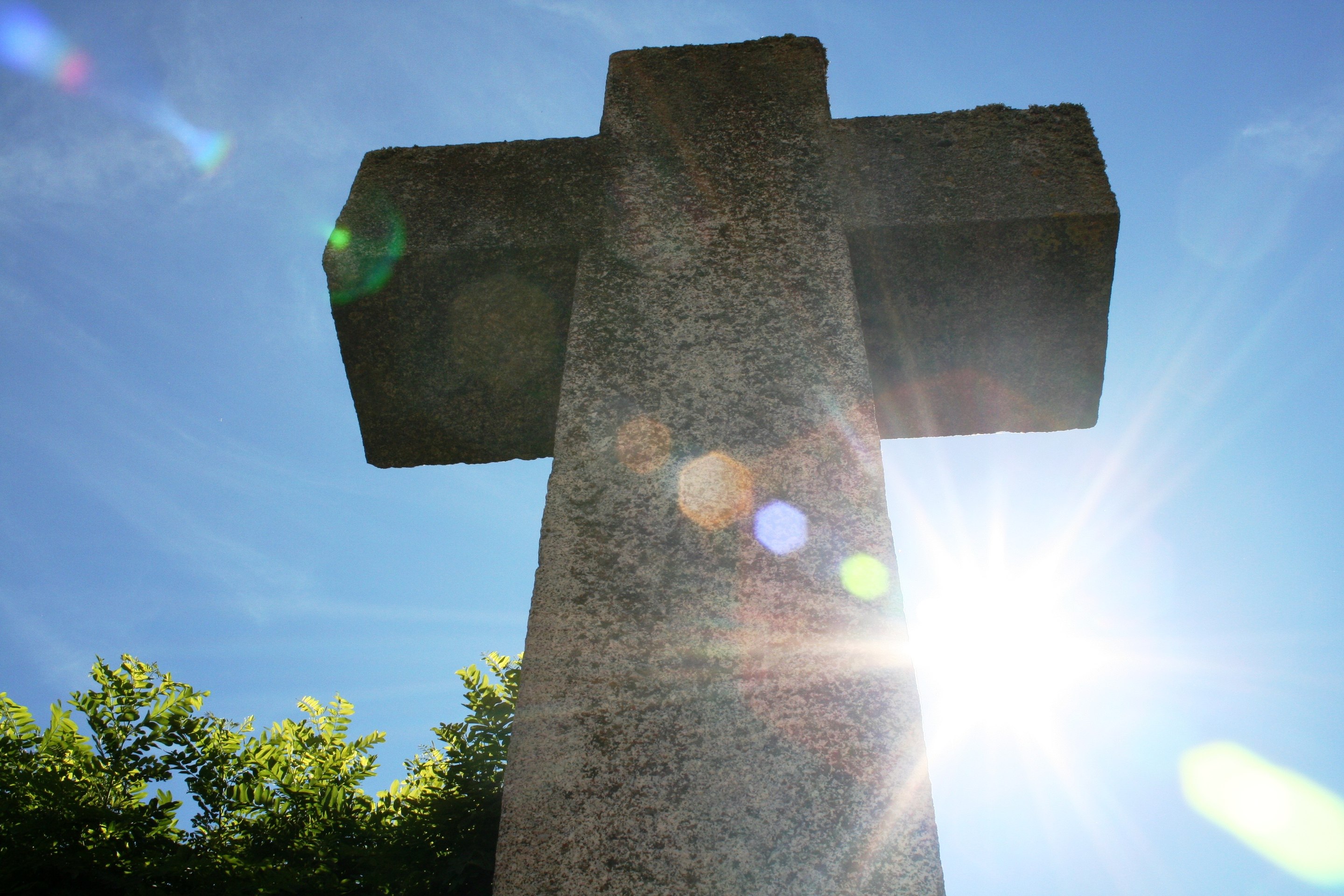 Sunlight shining behind stone cross
