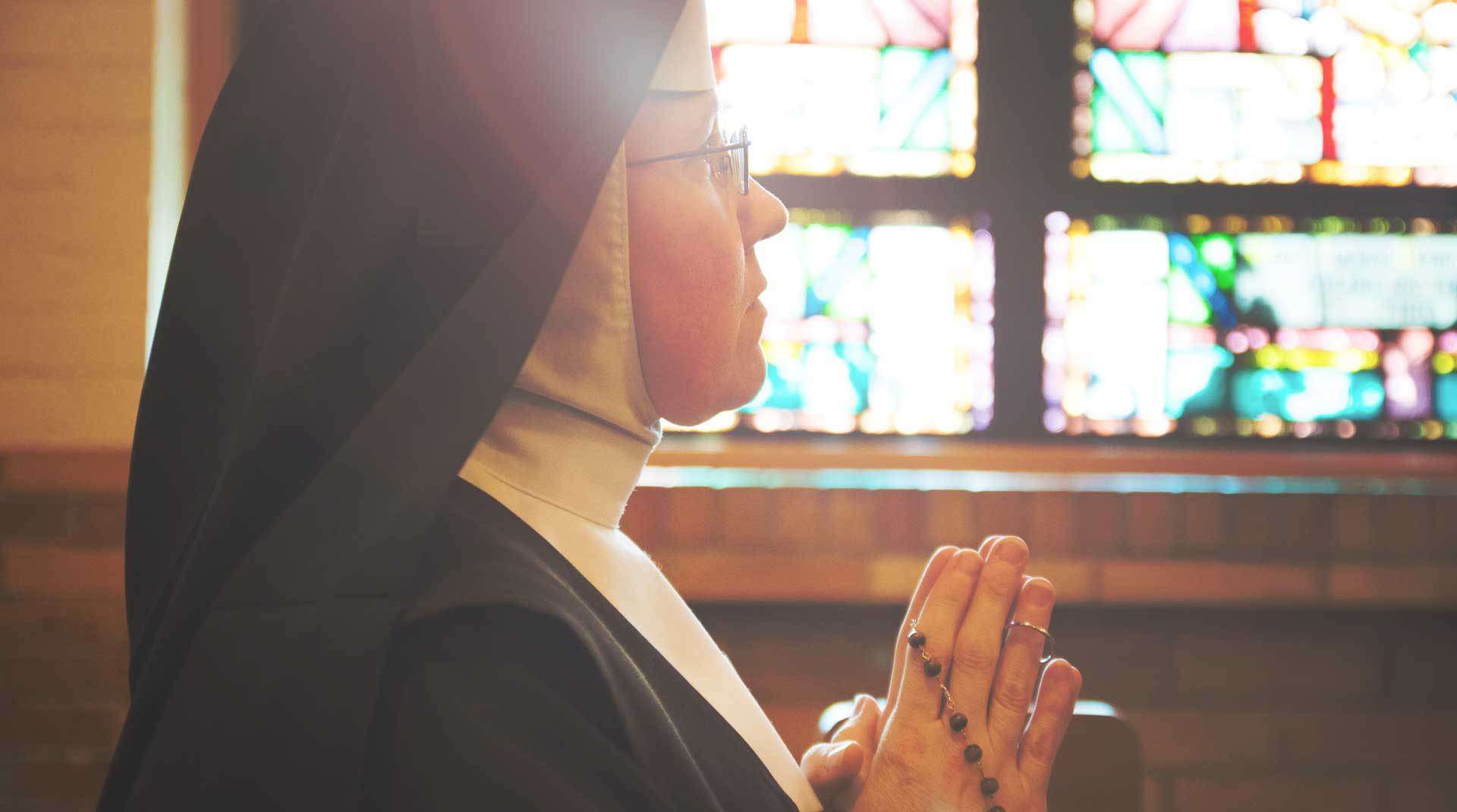 Sister praying in chapel holding rosary
