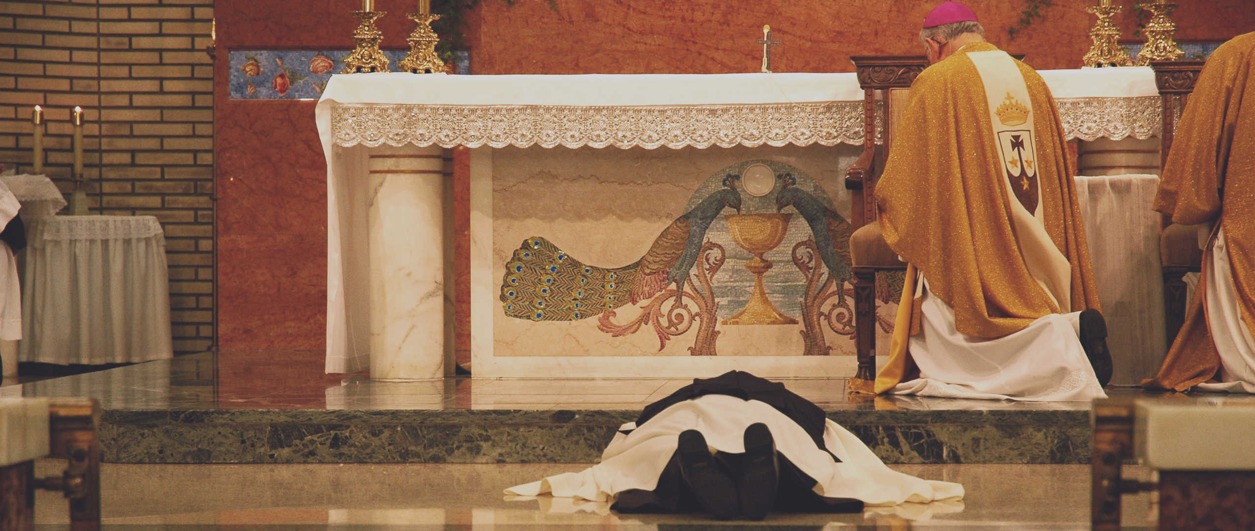 Sister laying prostrate in front of altar with bishop kneeling