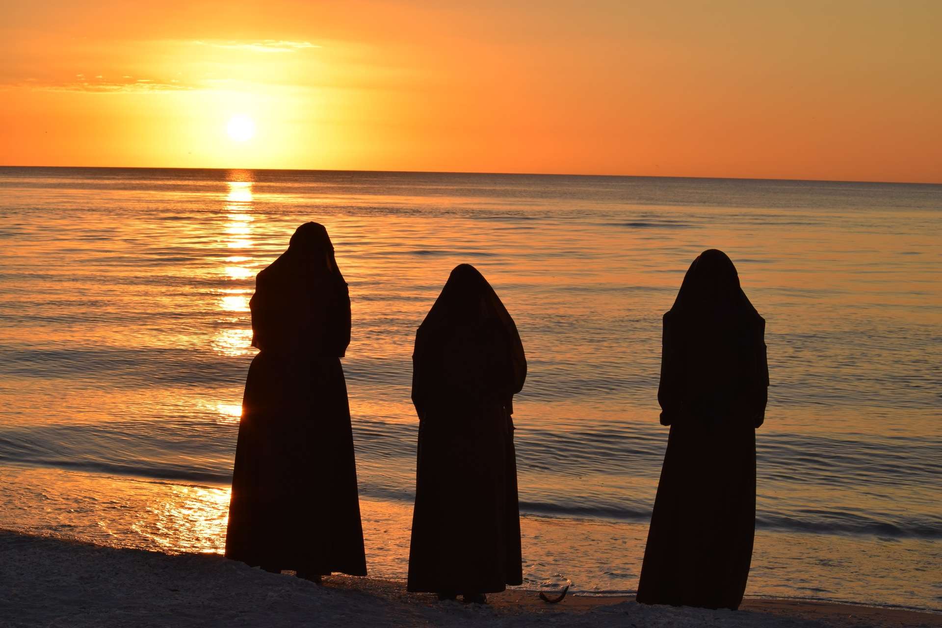 Sisters facing sunset on beach