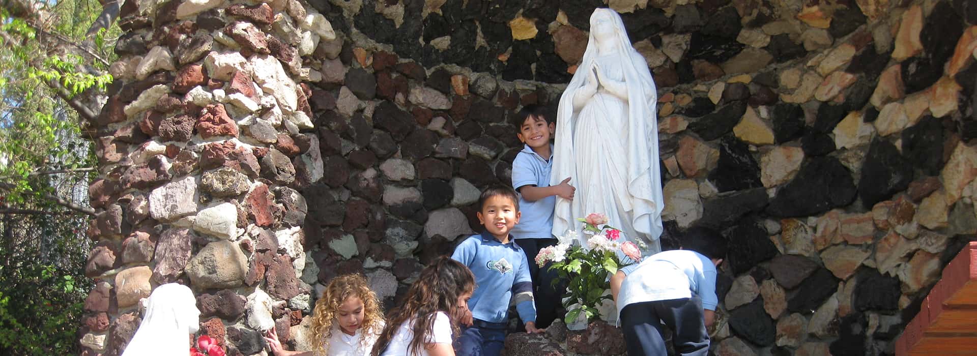 children around Mary statue in grove