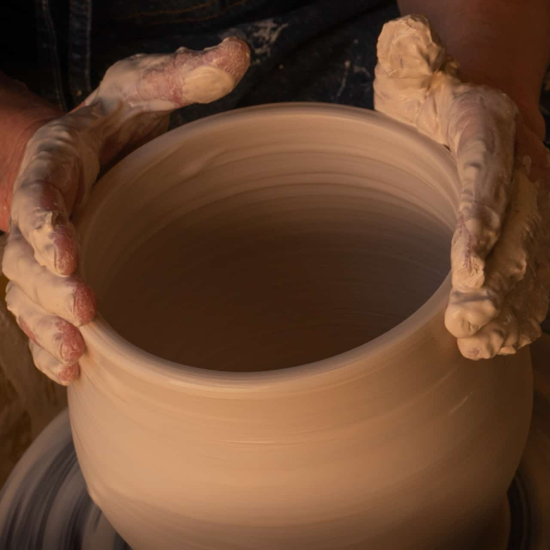 Hands molding clay jar