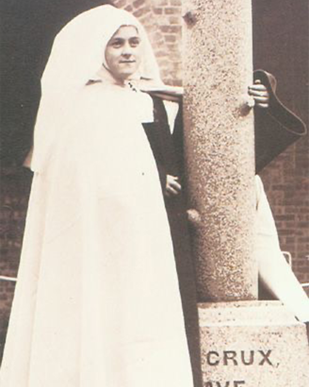 St. Therese in Carmelite Habit by a stone column.